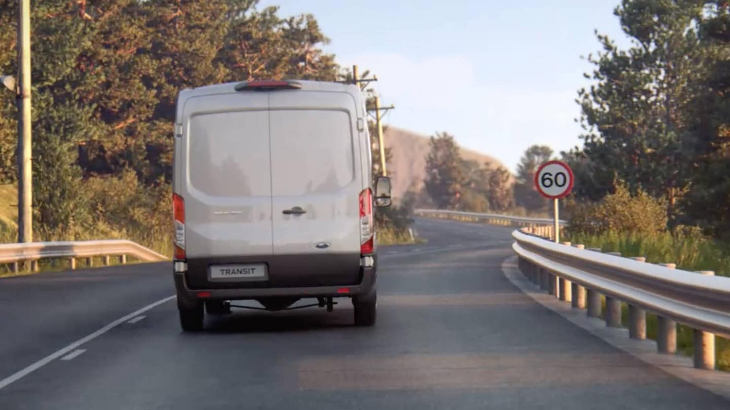 Ford Transit Van roulant sur une route, avec panneau de signalisation, vue de l’arrière