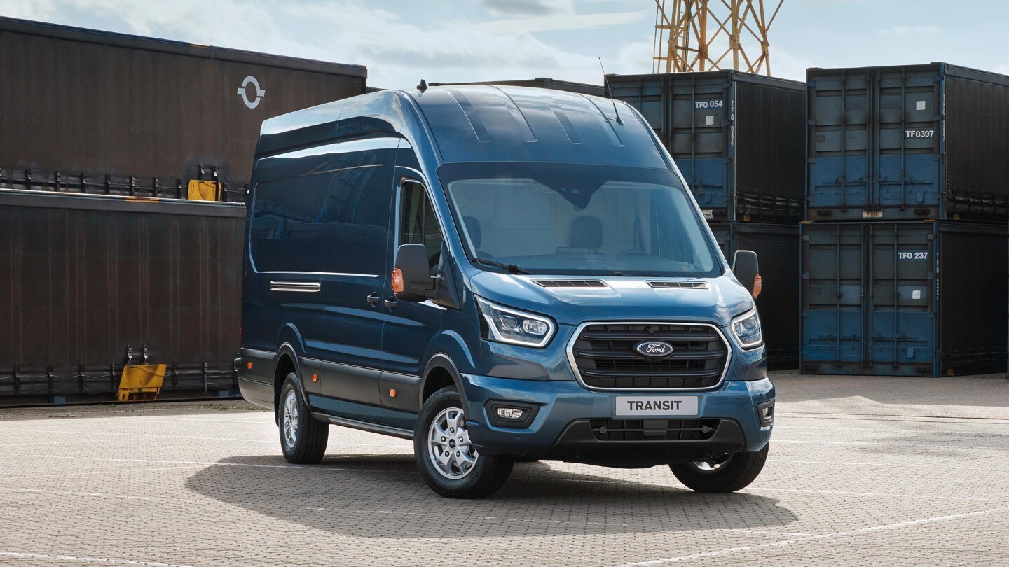 Transit Van standing in loading areaFord Transit Fourgon couleur bleue, vue de face aux trois quarts, stationnant devant des conteneurs