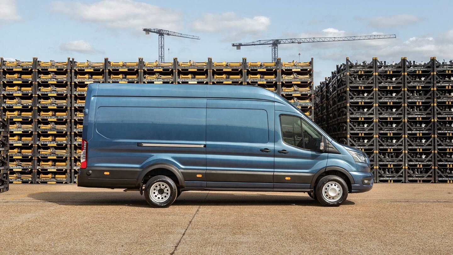 Ford Transit, camion de 5 tonnes, vue latérale bleue, garé sur une aire d’entreprise devant des piles de palettes