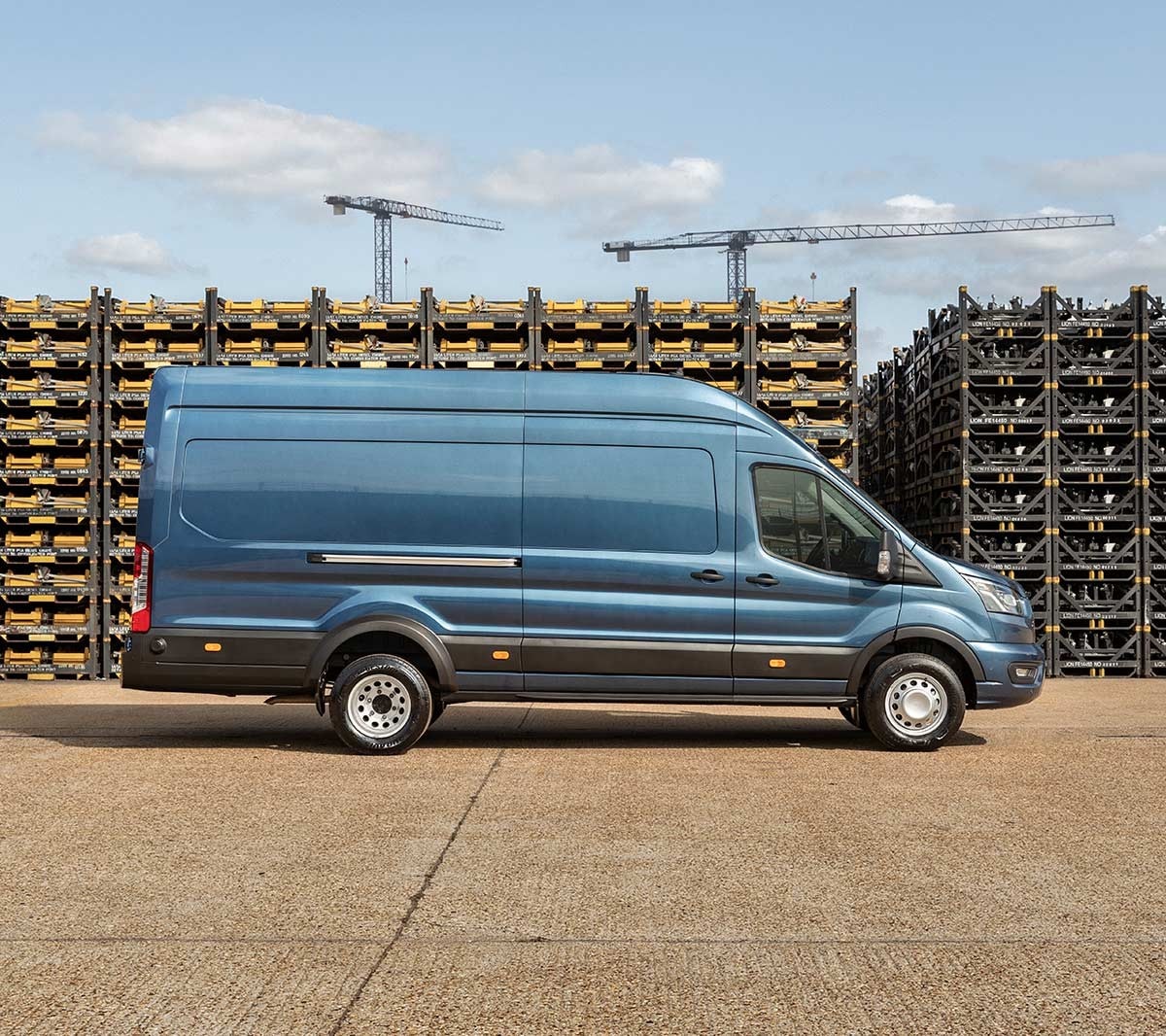 Vue latérale sur un Ford Transit camion-fourgon bleu de 5 tonnes, garé sur un site d’entreprise devant des piles de palettes