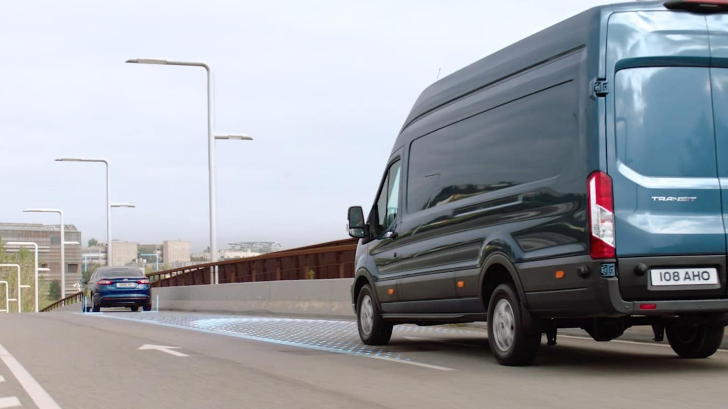 Ford Transit Fourgon couleur bleue, vue arrière aux trois quarts, roulant sur une voie rapide