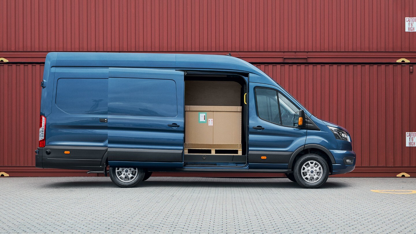 Ford Transit Fourgon couleur bleue, vue latérale, porte latérale coulissante ouverte, stationnant devant des conteneurs.