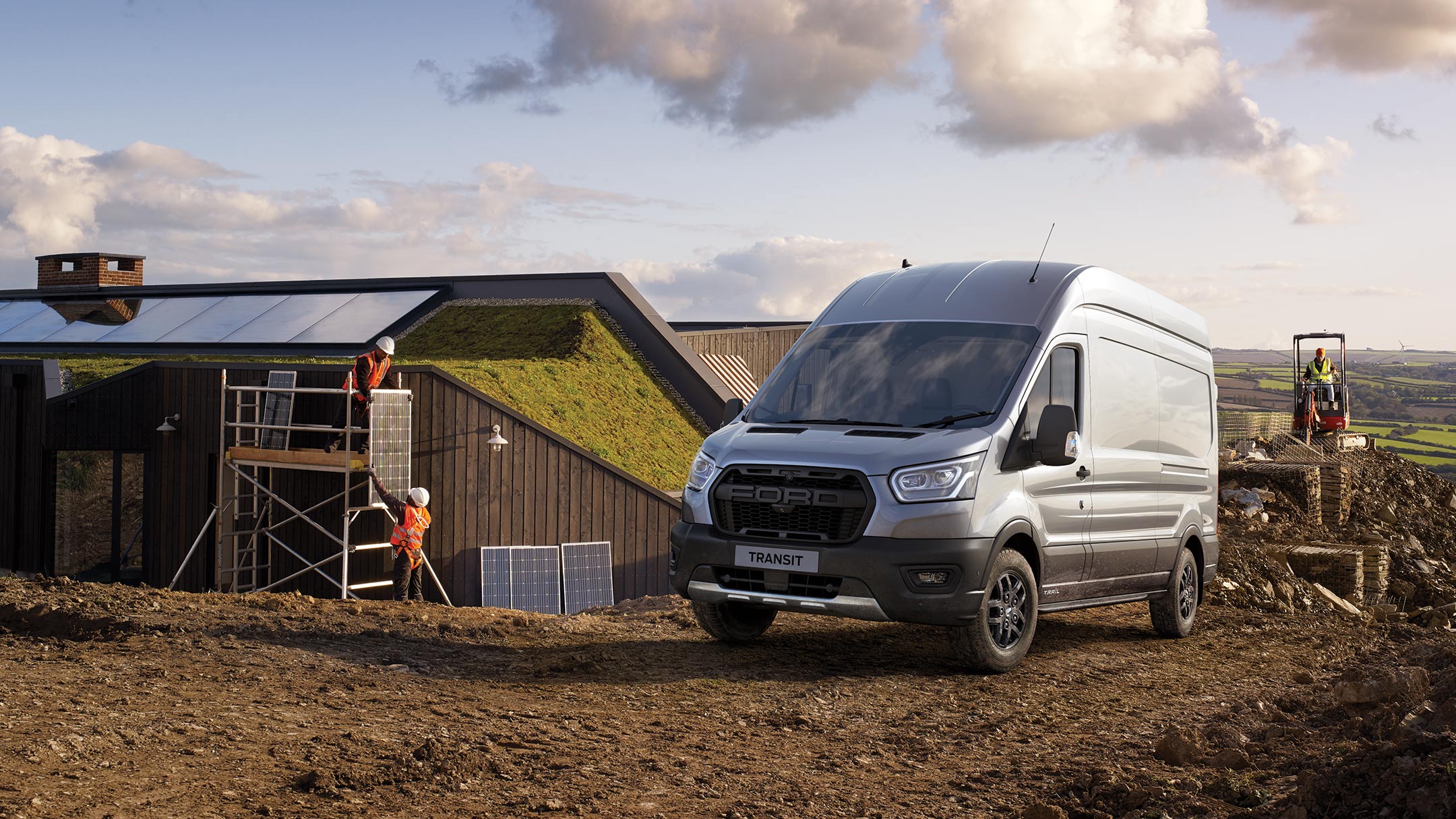 Fourgon Ford Transit Trail argent. Vue ¾ avant. Stationnement sur un chantier dans une région rurale