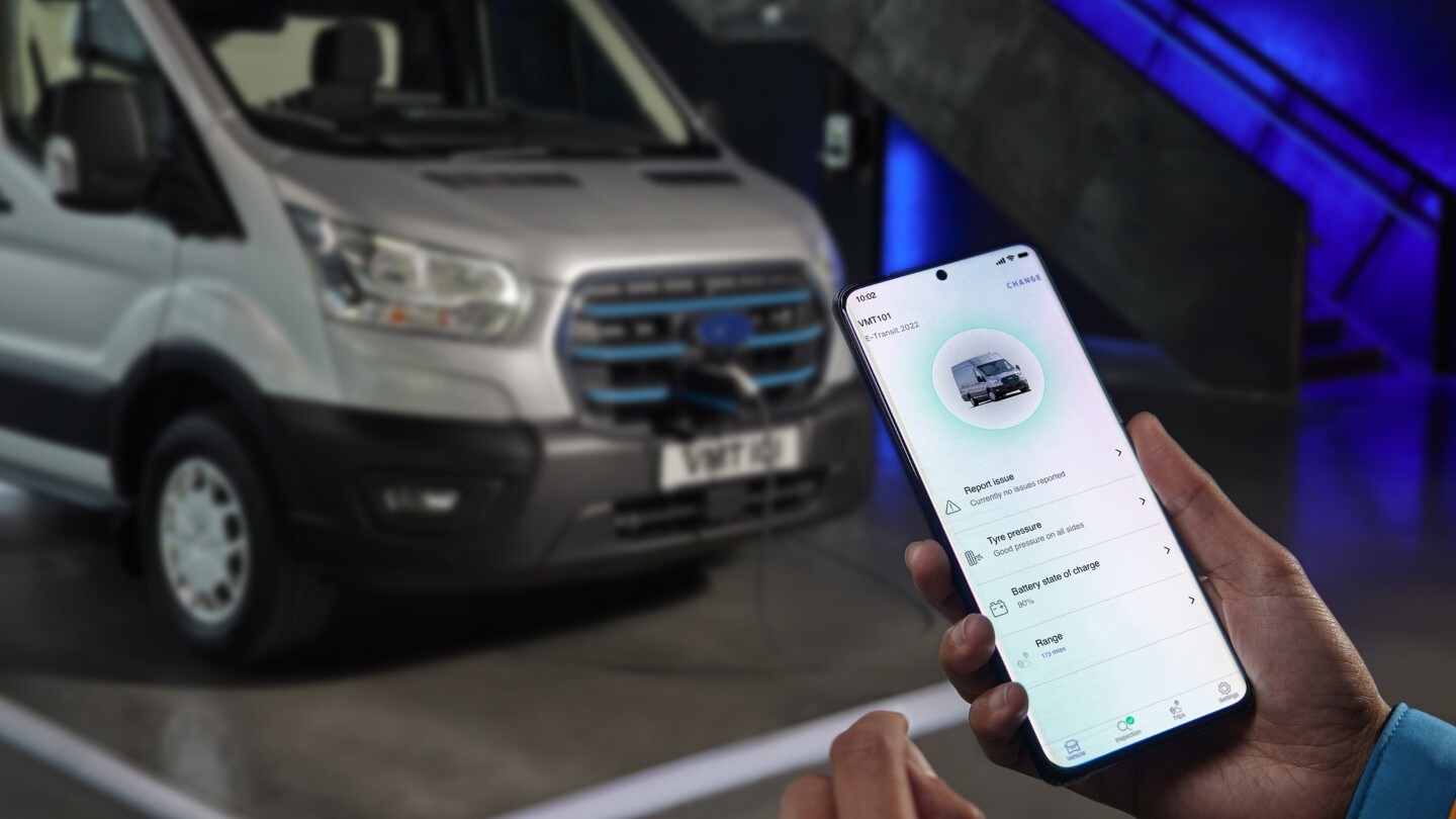 Ford E-Transit couleur argent, vue de face aux trois quarts et main tenant un smartphone