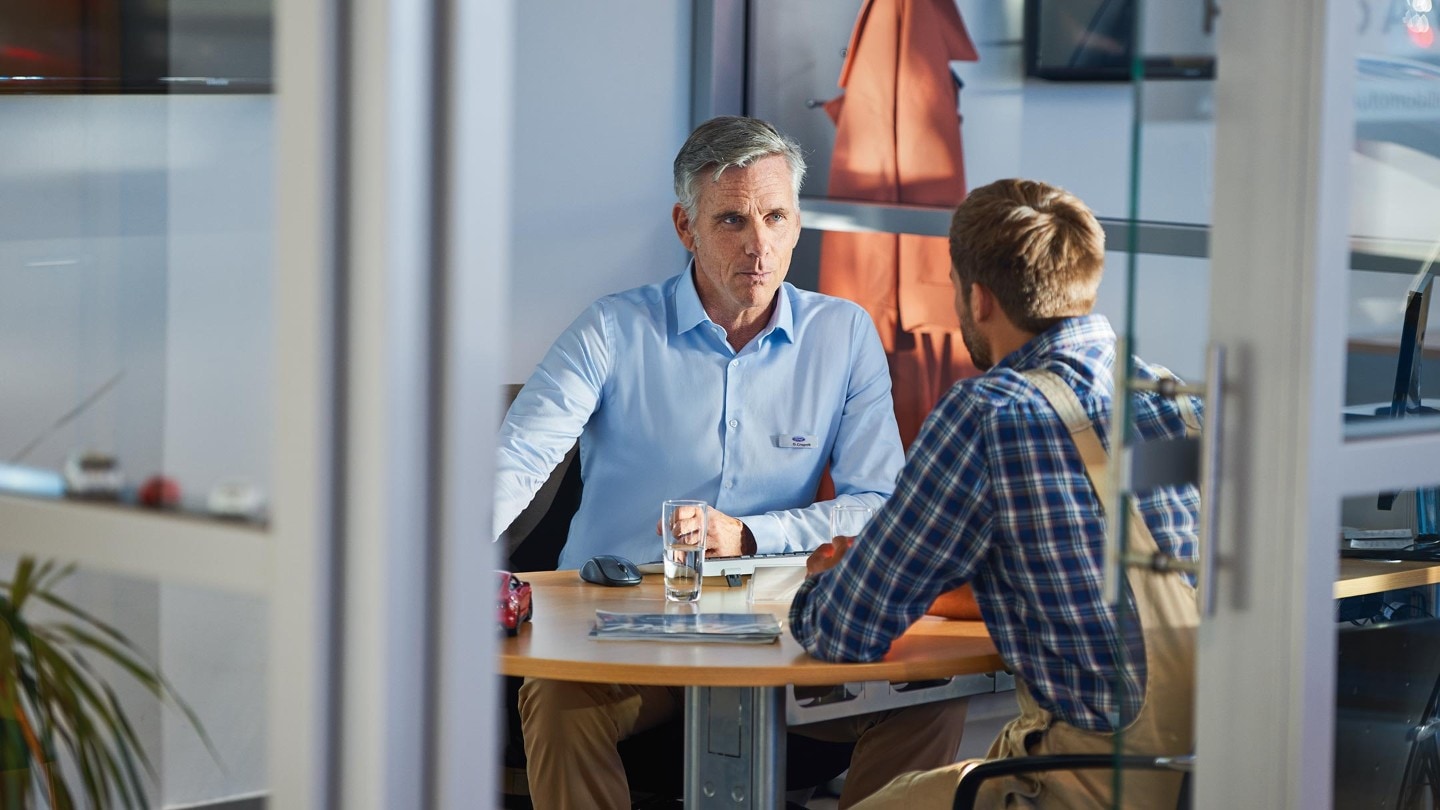 Deux personnes sont assises face à face à un bureau