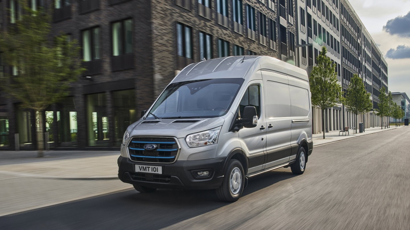 Ford E-Transit argent, vue de face aux trois quarts, roulant en ville