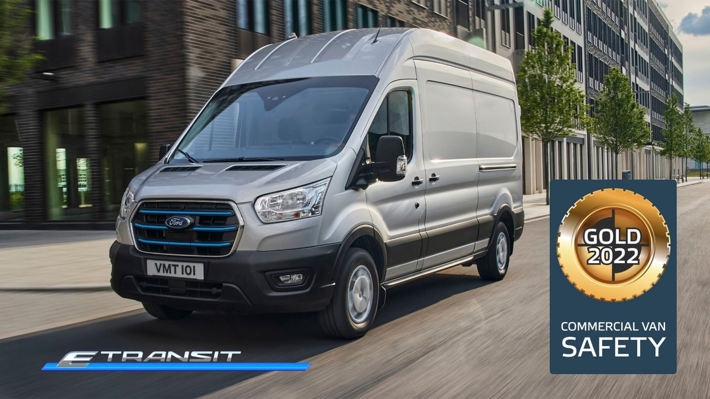 Ford E-Transit Fourgon couleur argent, vue latérale aux trois quarts, roulant le long de tours et logo NCAP Gold pour la catégorie «Sécurité»