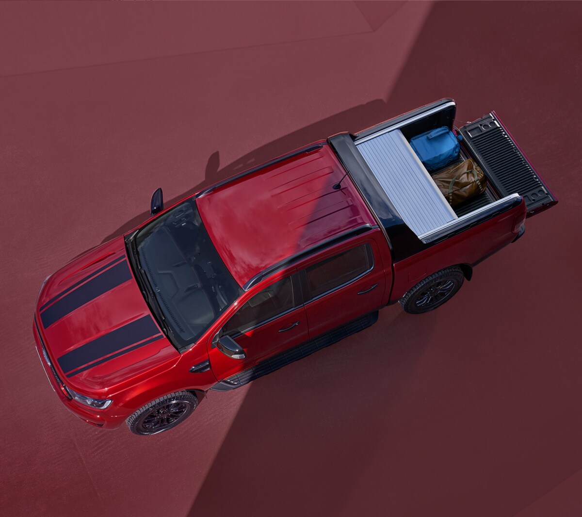 Ford Ranger Stormtrak rouge, vue aérienne, cache-bagages ouvert, garé sur fond rouge 