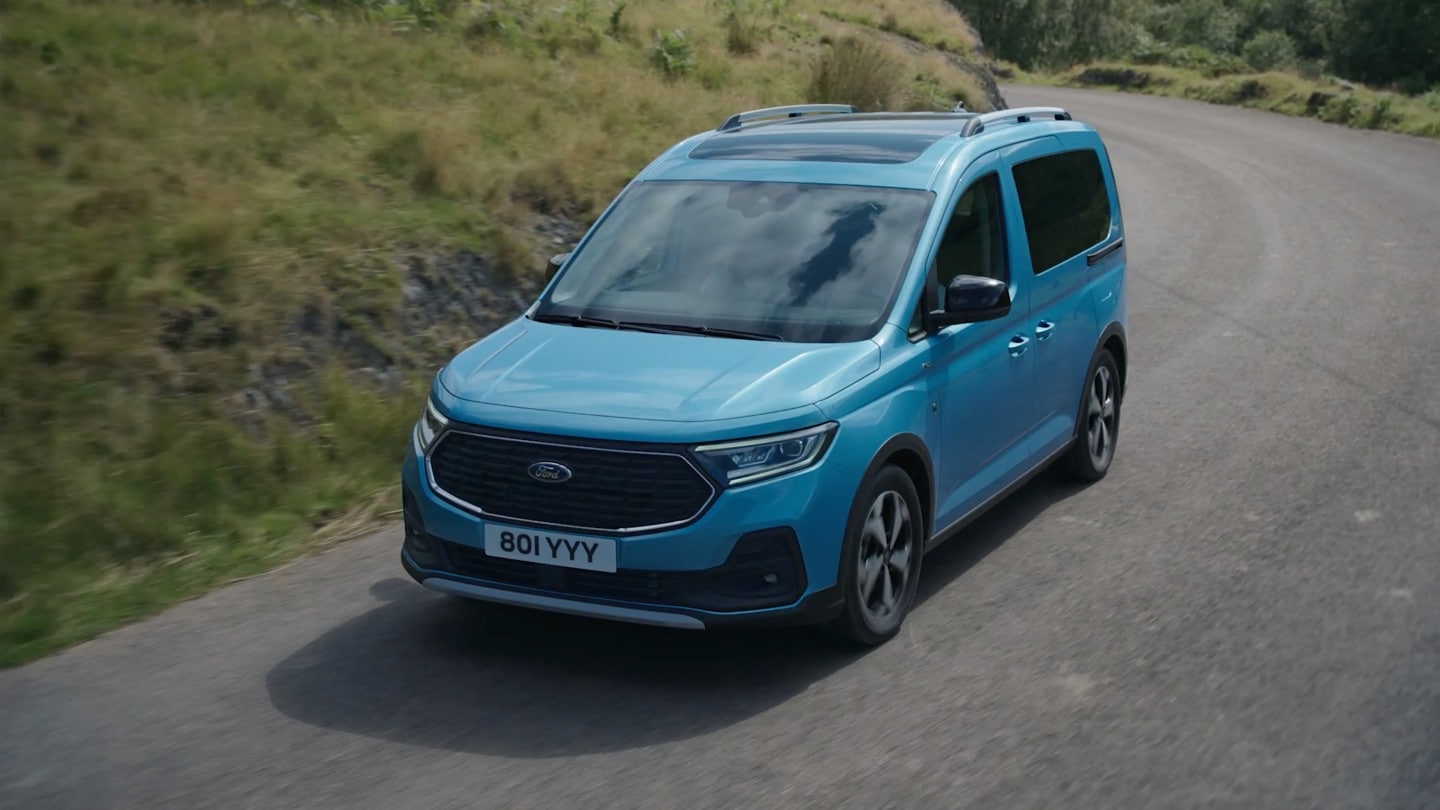 Ford Tourneo Connect couleur bleu clair, vue de face aux trois quarts, roulant sur une route de campagne