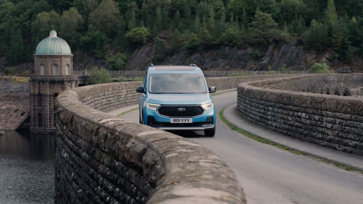 Ford Tourneo Connect, couleur bleu clair, vue de face, traversant un pont en pierre sinueux