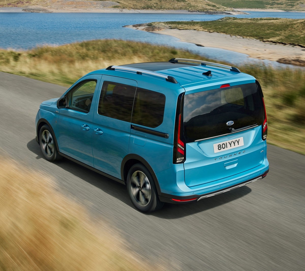 Ford Tourneo Connect couleur bleu clair, vue arrière aux trois quarts, roulant sur une route de campagne