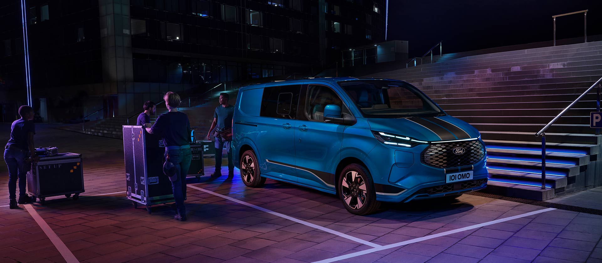 Une camionnette électrique Ford E-Transit Custom bleue est chargée pendant la nuit.