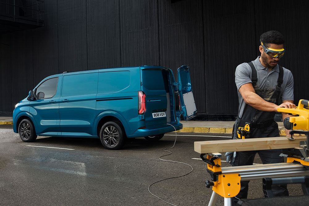Une camionnette Ford Transit Custom bleue et une personne avec un outil électrique.