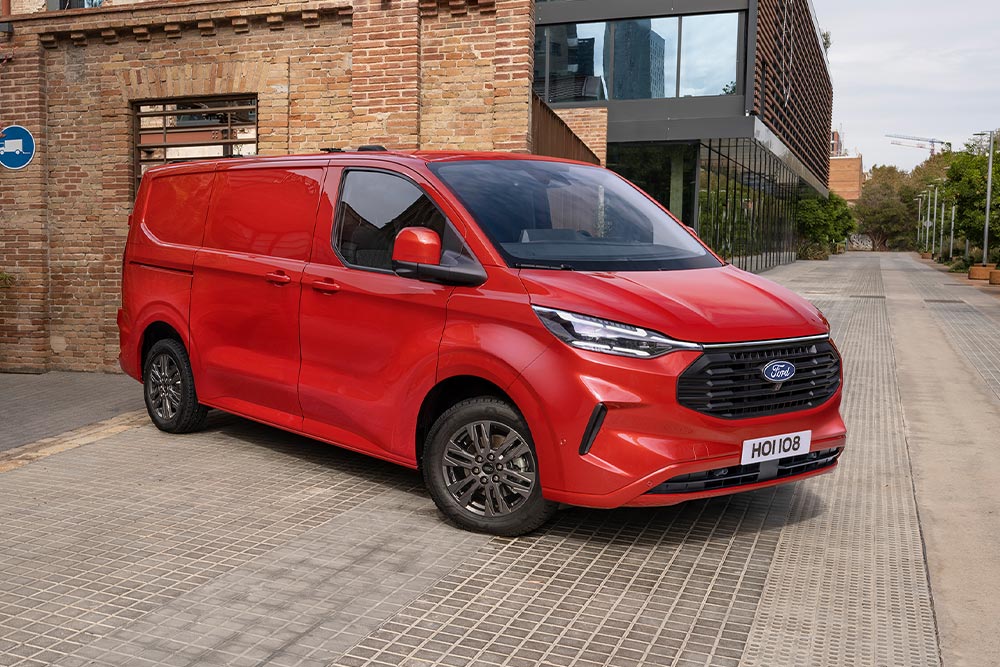 Camionnette Ford Transit Custom rouge garée dans une rue de la ville.