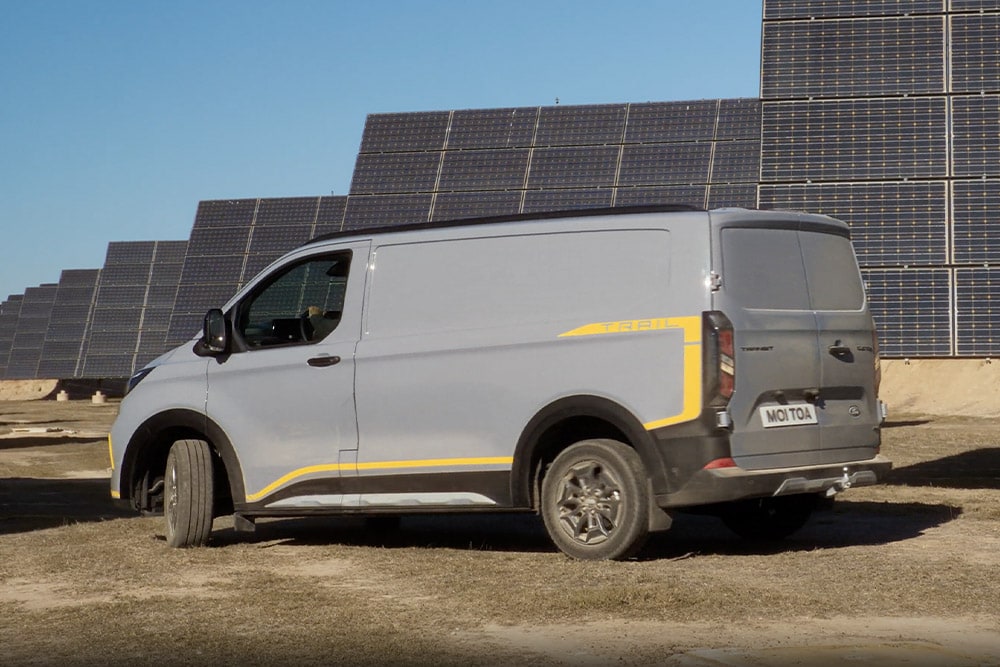 Fourgon Ford Transit Custom Trail gris avec des accents jaunes.