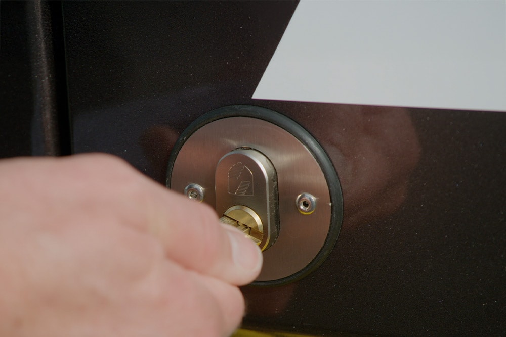 Une main verrouille la porte du fourgon à l'aide d'une clé.