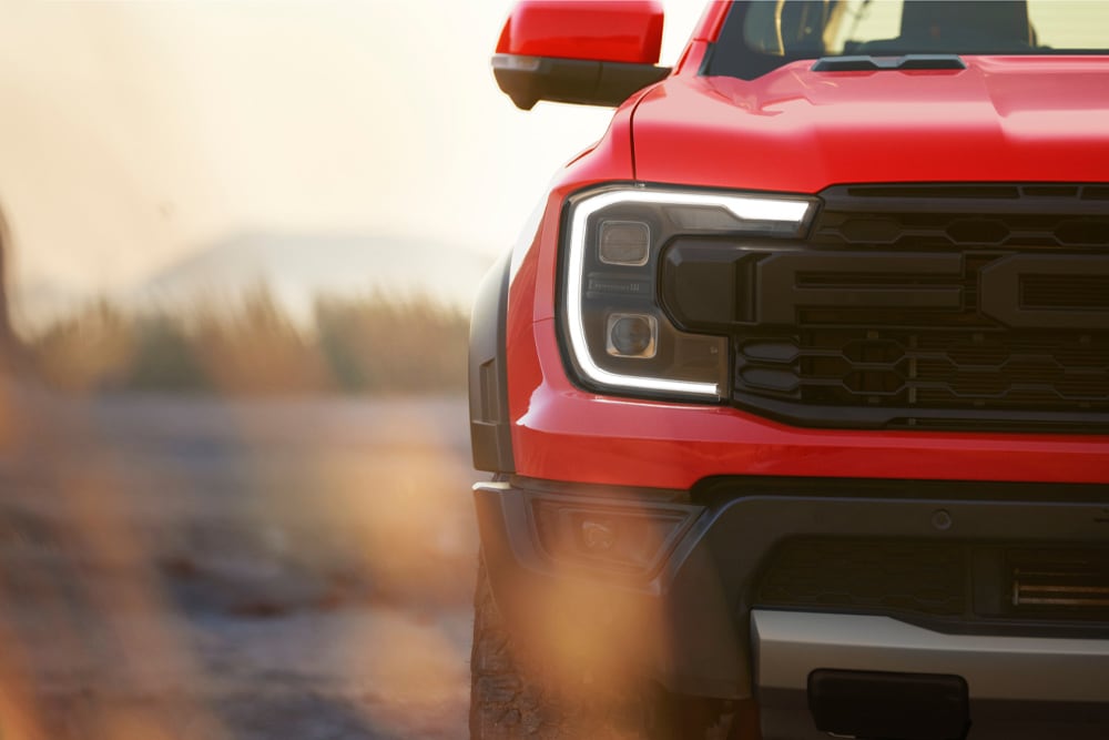 Gros plan sur la calandre avant d’un Ford Ranger Raptor rouge.