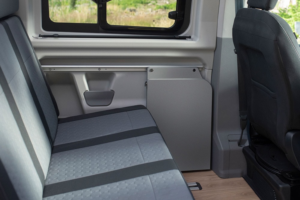Banquette grise réglable et chauffante de la deuxième rangée dans le Ford Nugget.