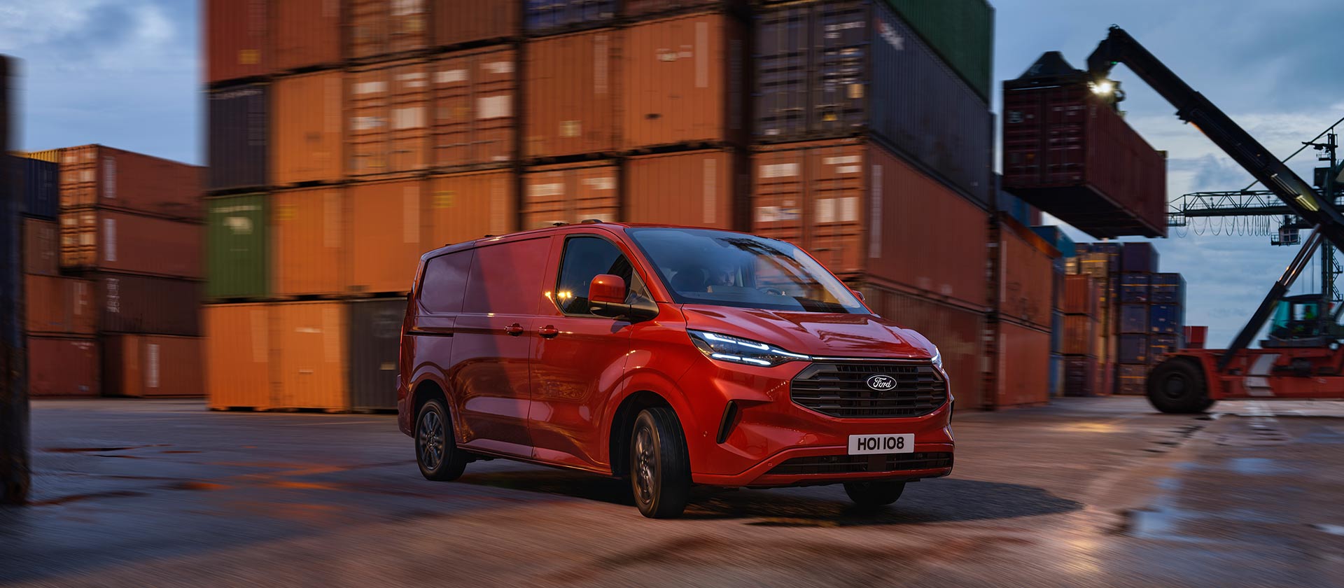 Une camionnette Ford Transit Custom rouge circule dans une zone portuaire