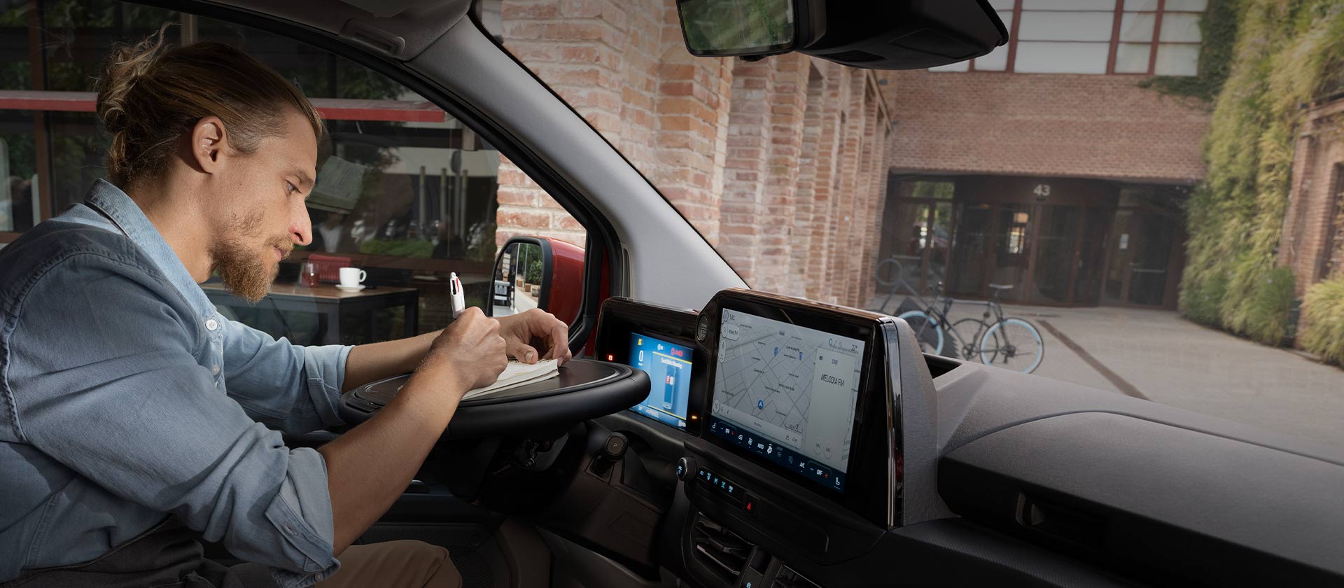 Une personne écrit dans un carnet à l'intérieur du Ford Transit Custom.