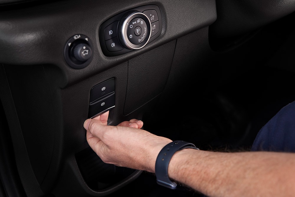 Gros plan d'une main appuyant sur un bouton sur le tableau de bord d'un fourgon électrique Ford E-Transit.