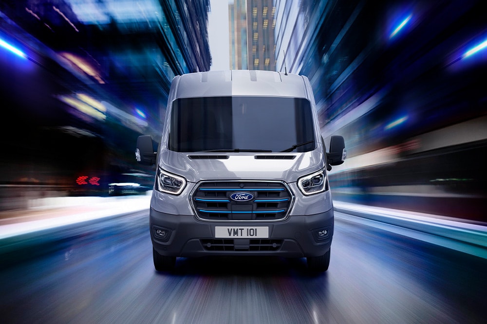 Fourgon électrique Ford E-Transit gris foncé circulant sur une route.