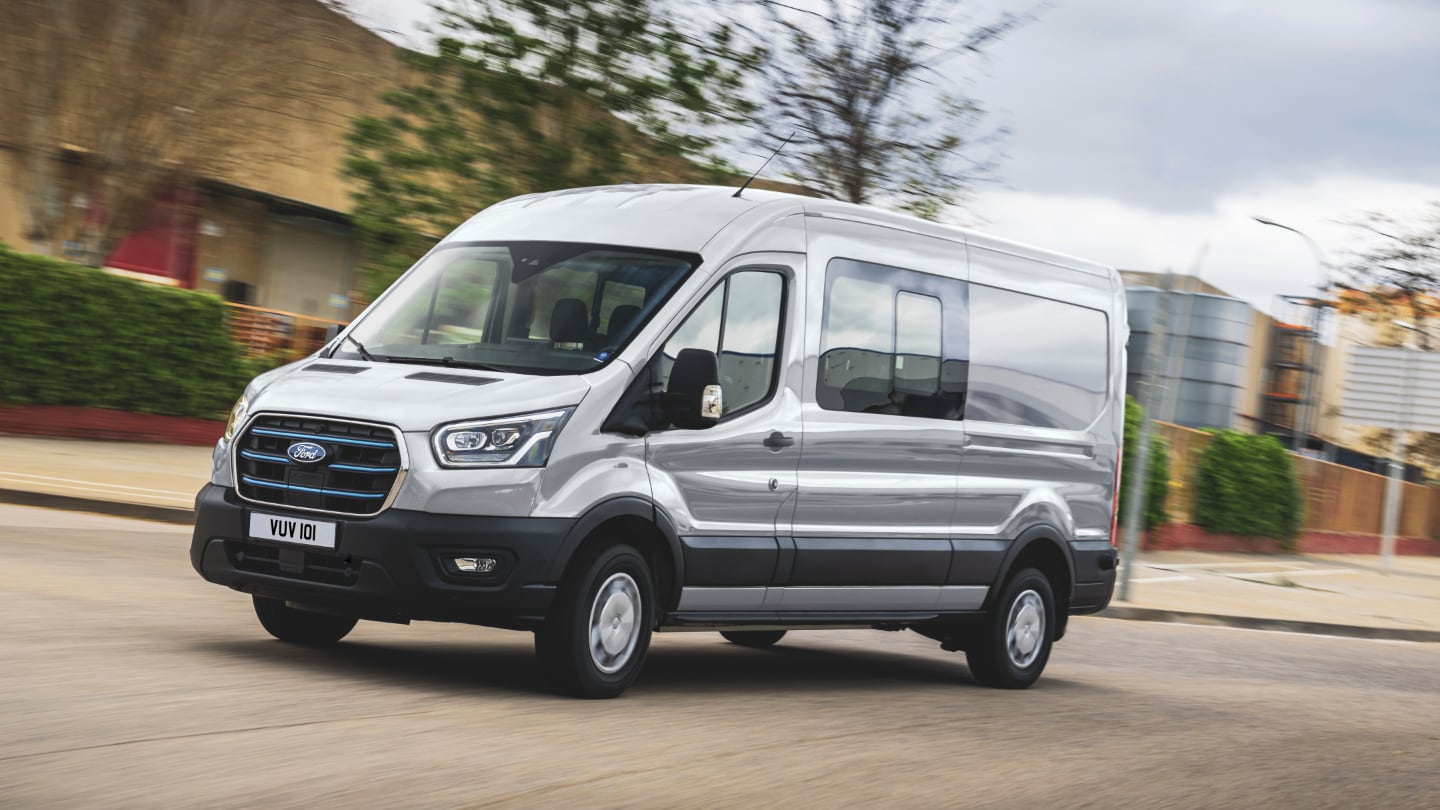Ford E-Transit Châssis cabine couleur blanche, vue de face aux trois quarts, roulant sur une route de campagne
