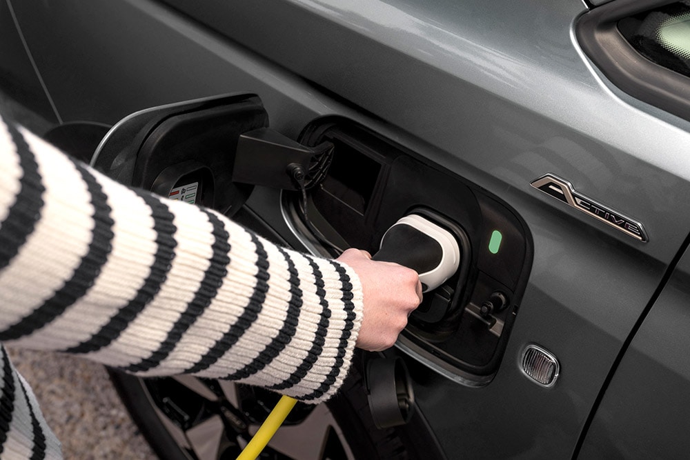 Une personne branchant un câble de recharge dans un Ford Transit Connect  hybride rechargeable.
