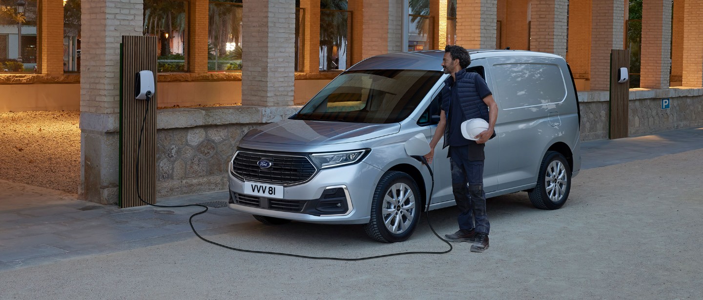 Homme en train de charger un Ford Transit Connect couleur argent garé sur le bord de la route
