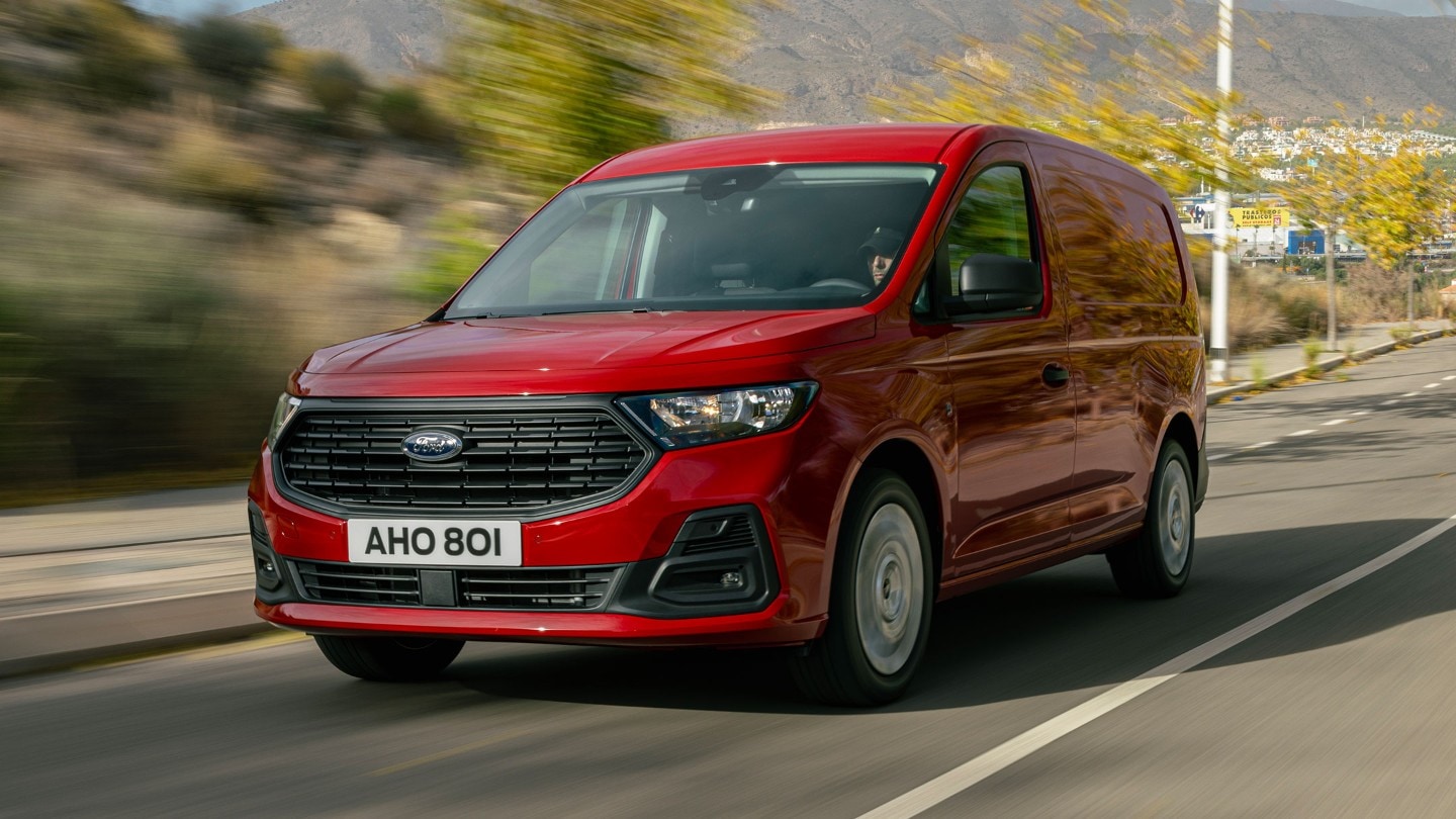 Un Ford Transit Connect en Maple Red avec calandre et phares roule sur une route. 