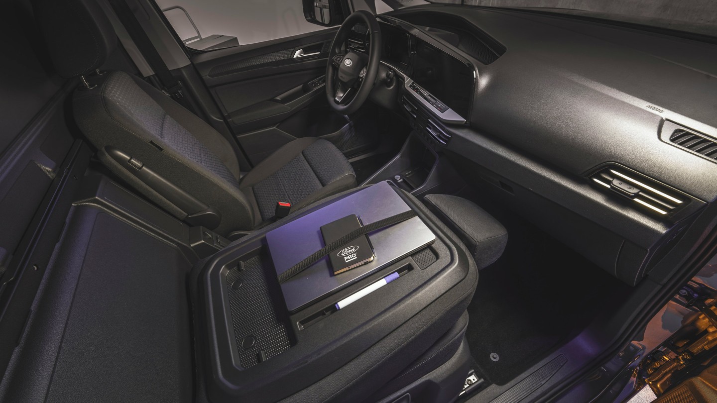 Un ordinateur portable et un calepin Ford Pro sont posés sur la table de travail du Ford Transit Connect.