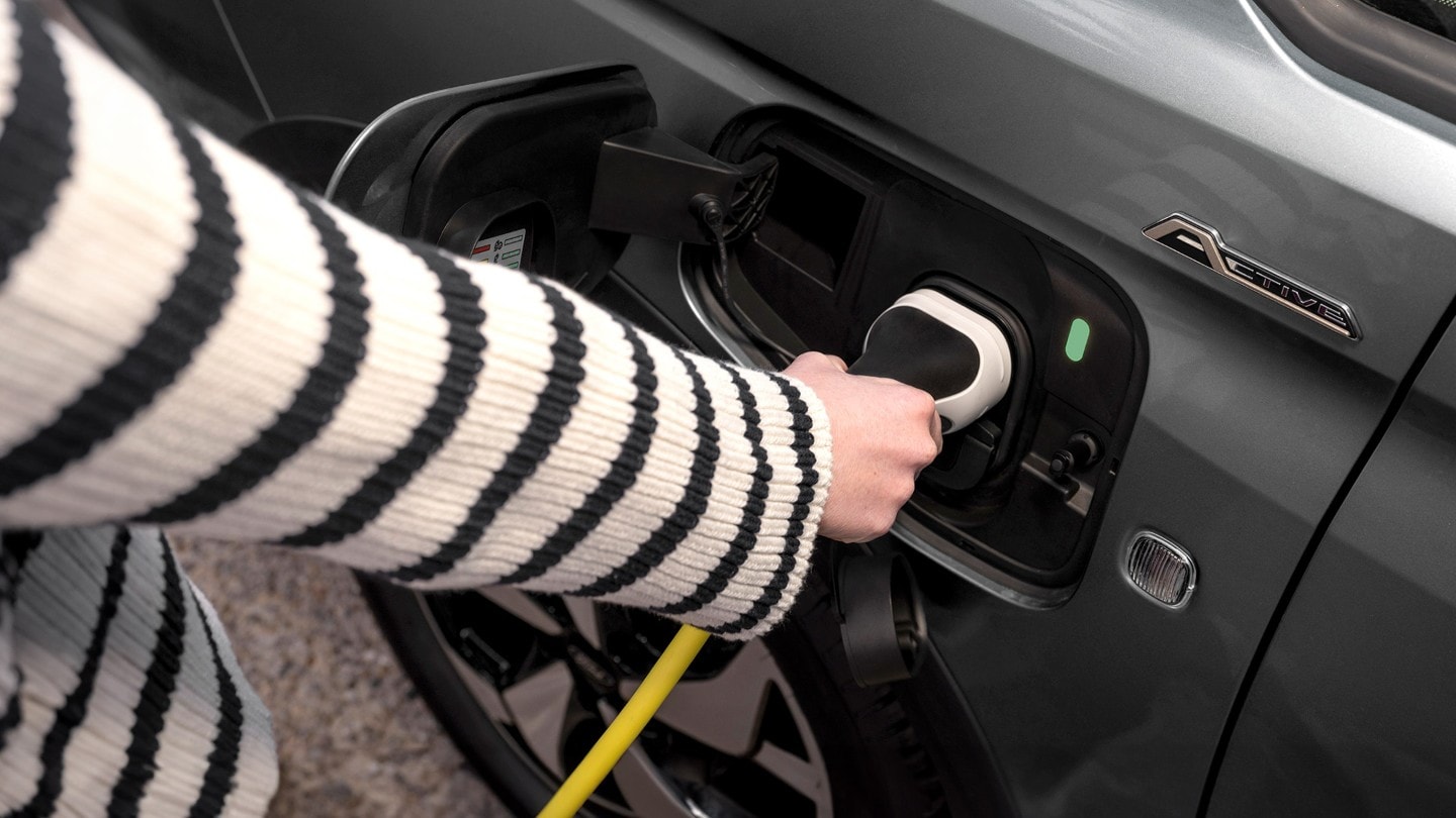 Un câble de recharge est branché dans la prise du Ford Transit Connect en Boundless Blue. 