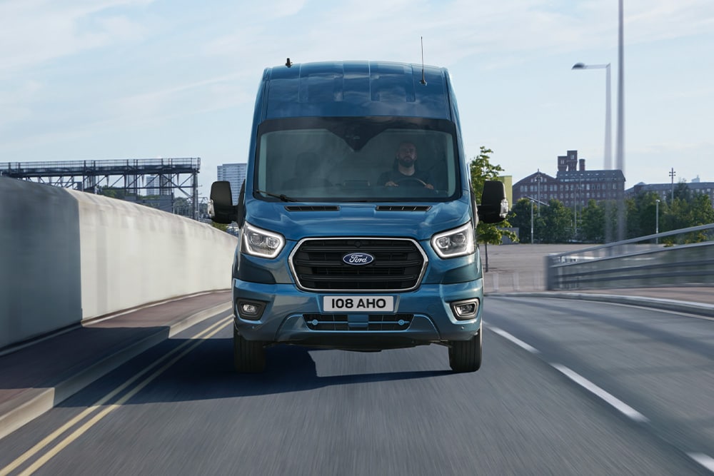 Vue de face d'un Ford Transit Fourgon bleu circulant sur une route.