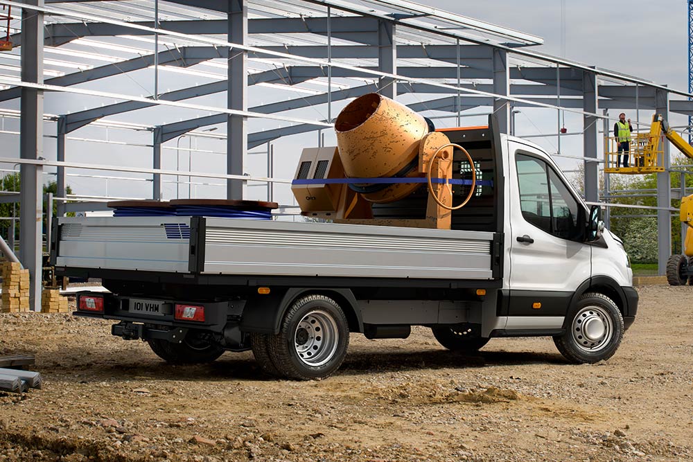 Châssis cabine Ford Transit transportant une bétonnière sur son plateau et stationné sur un chantier. 