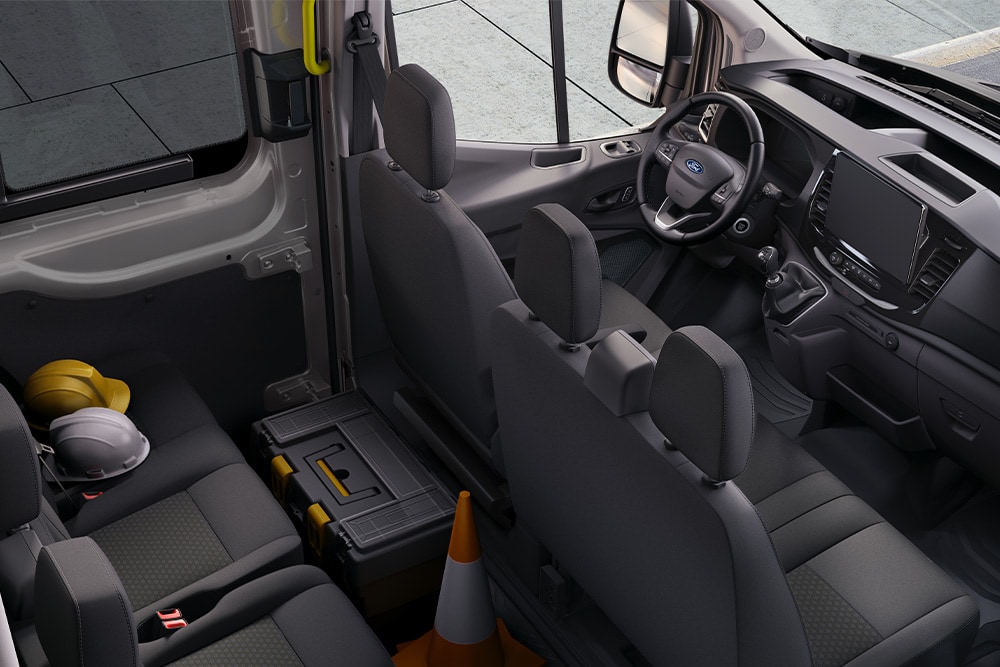 Intérieur du fourgon Ford Transit double cabine avec deux rangées de sièges.