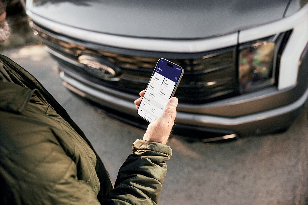 Homme regardant son smartphone devant un Ford Ranger.