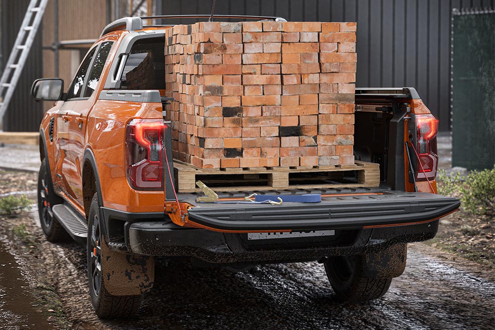Vue de l’arrière d’un Ford Ranger orange, avec un tas de briques chargé dans la benne.