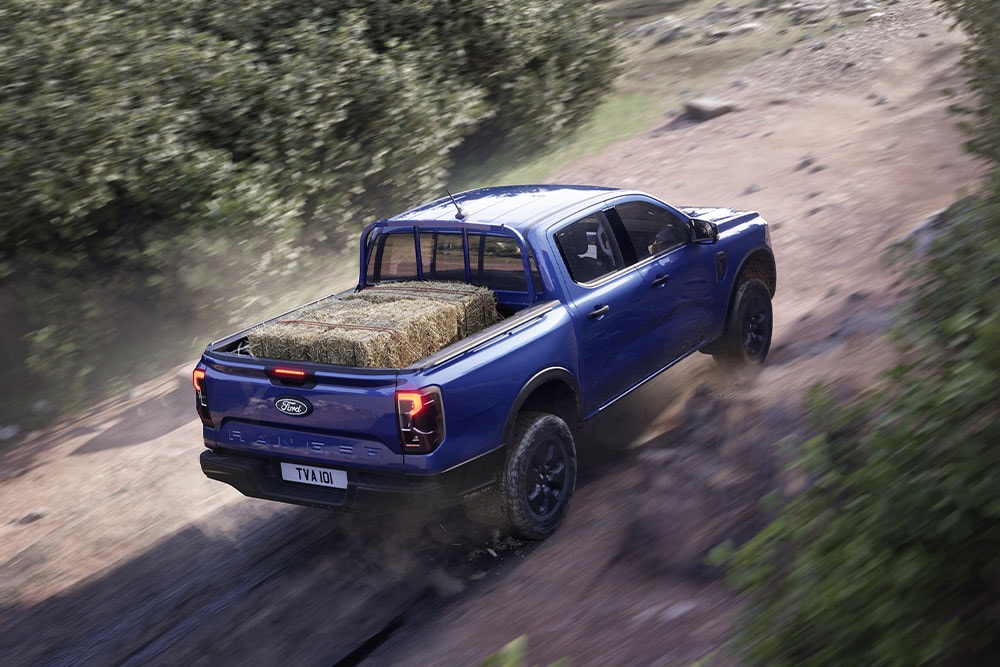 Vue de dessus arrière d'un Ford Ranger bleu roulant sur un chemin de terre.