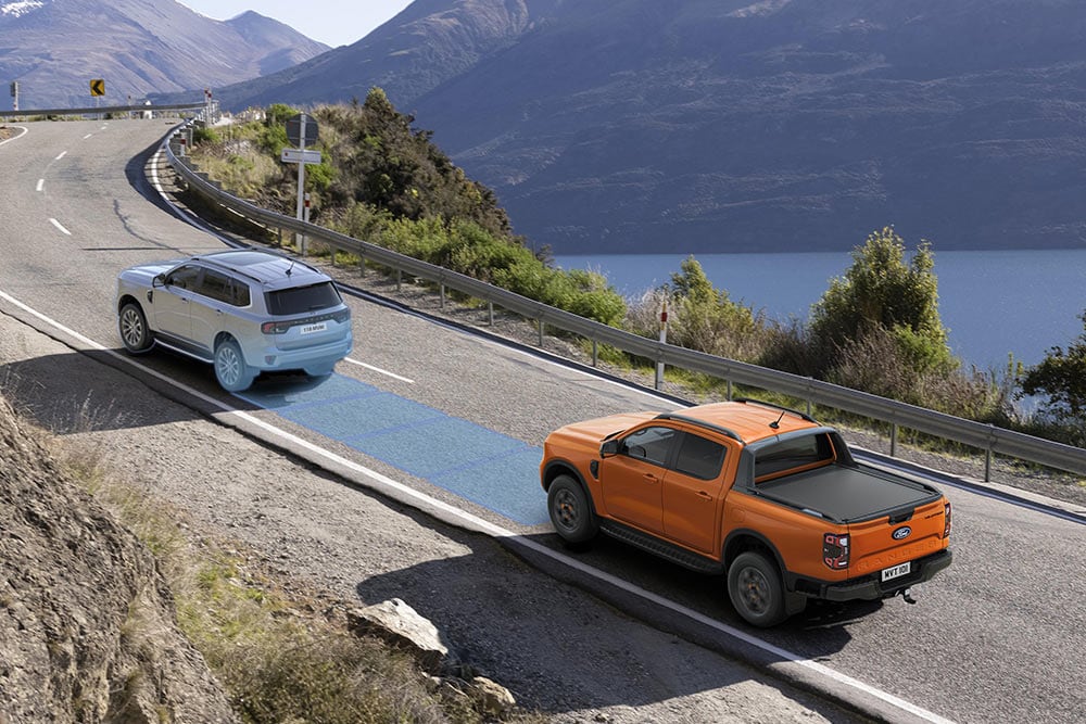 Un Ford Ranger orange utilise son système d’aide à la conduite de pointe sur une route côtière.