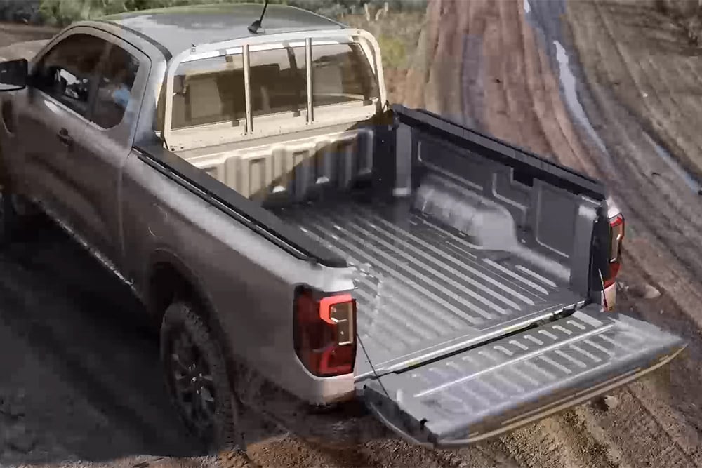 Ford Ranger XLT Super Cabine argenté garé sur une surface boueuse, hayon ouvert, vu de dessus.