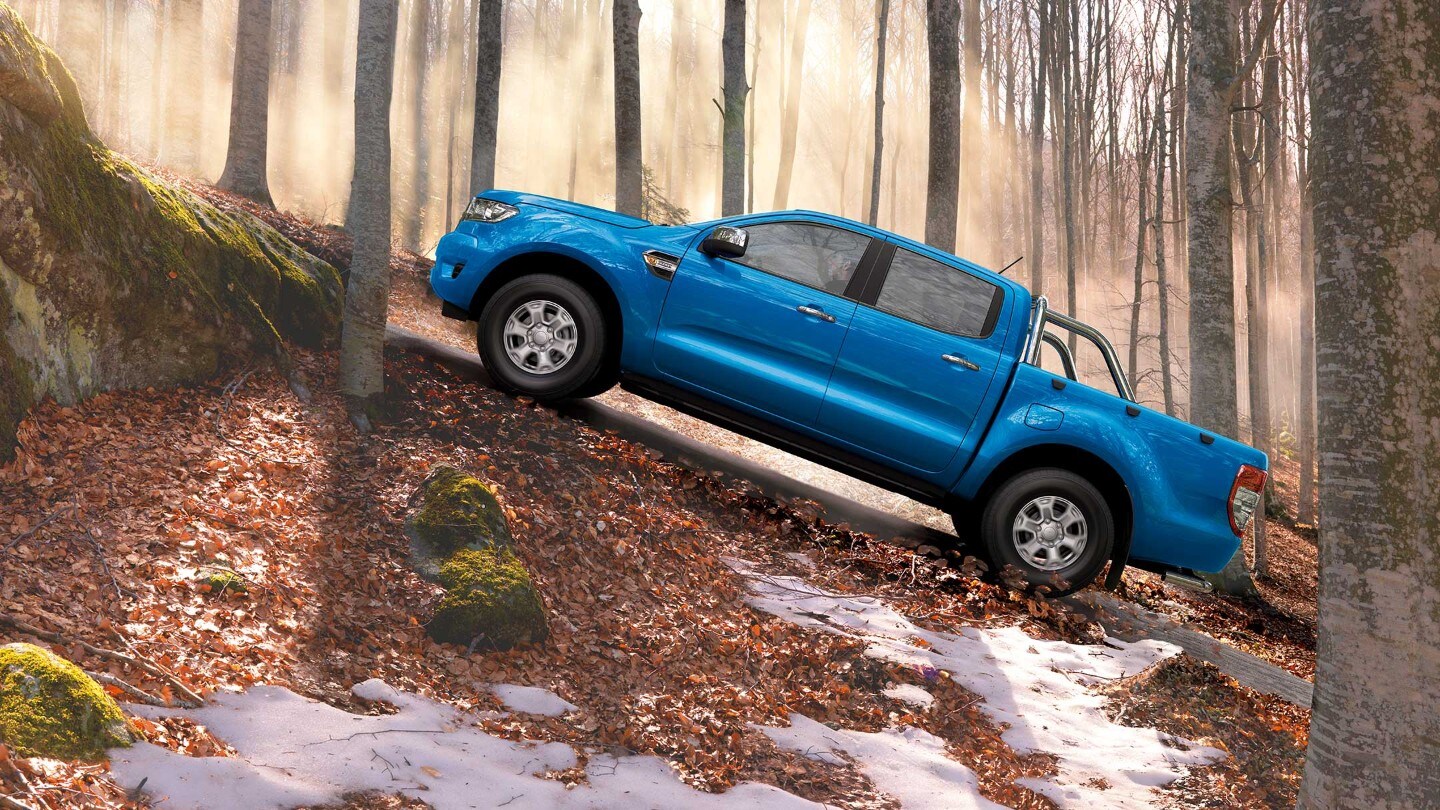 Ford Ranger couleur bleue, vue latérale, se garant sur un chemin de forêt en montée
