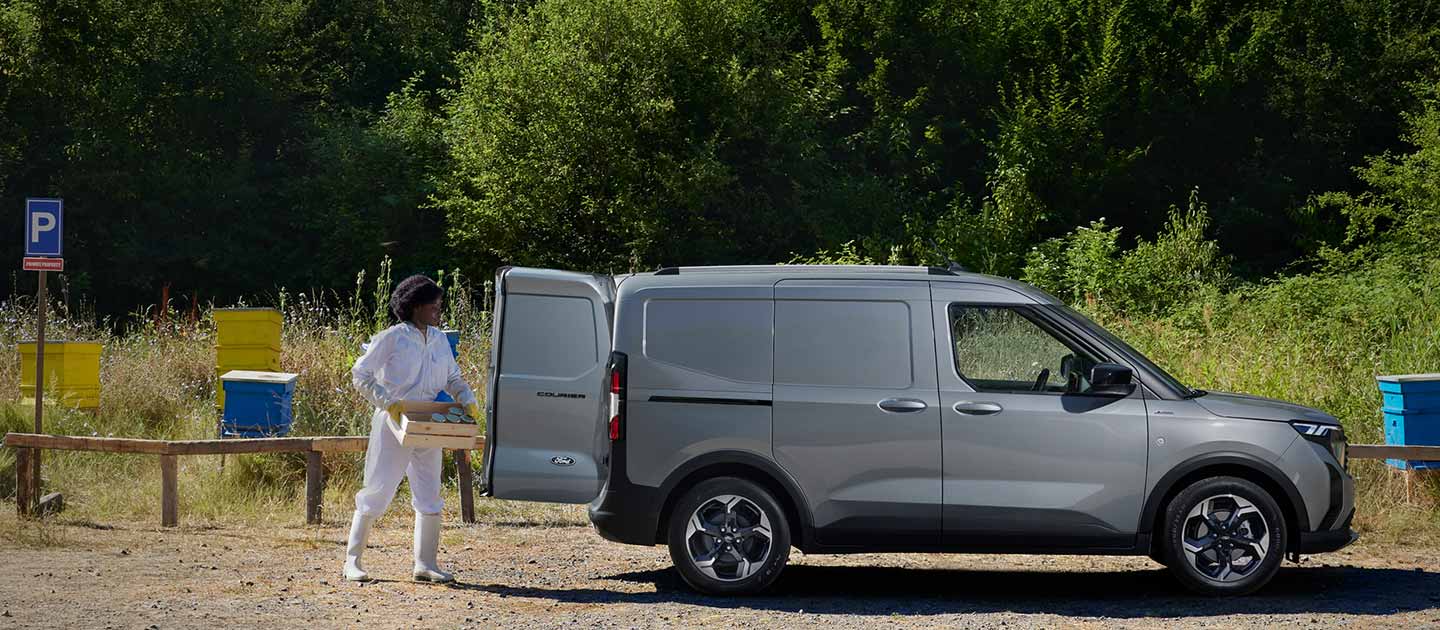 Ford E-Transit Courier couleur grise – Vue latérale, femme chargeant la voiture