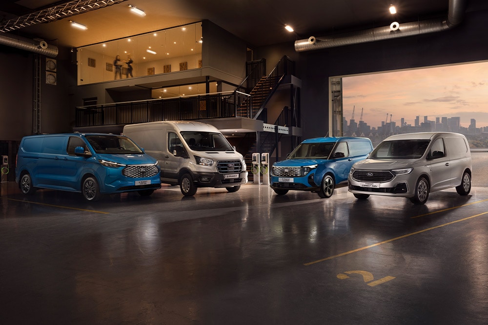 Flotte de Ford Transit dans un showroom avec une skyline urbaine au crépuscule en arrière-plan.