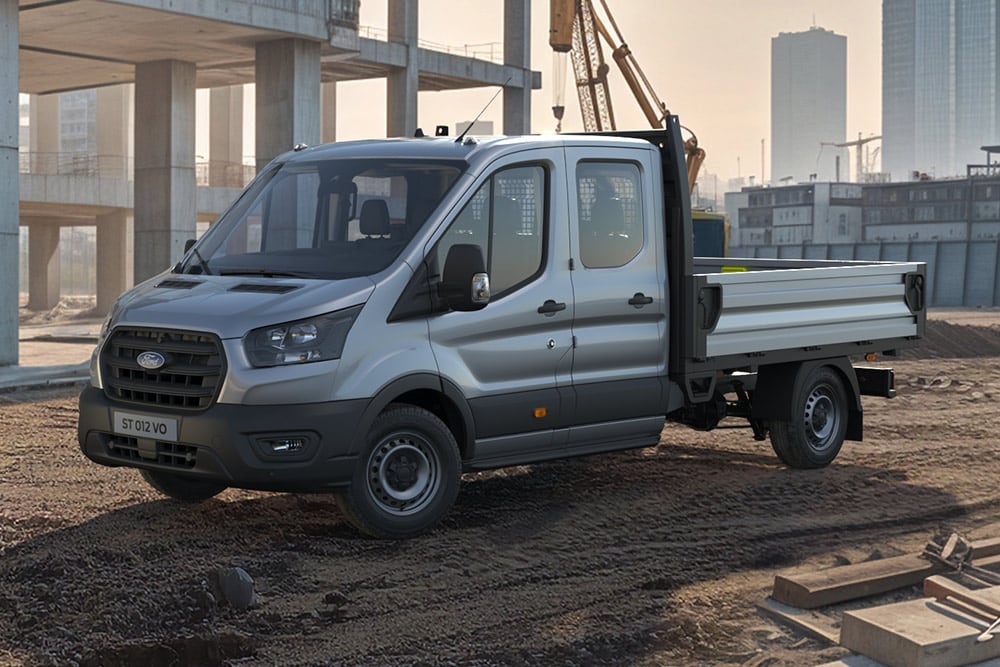Un châssis squelette Ford E-Transit blanc garé sur un chantier de construction.