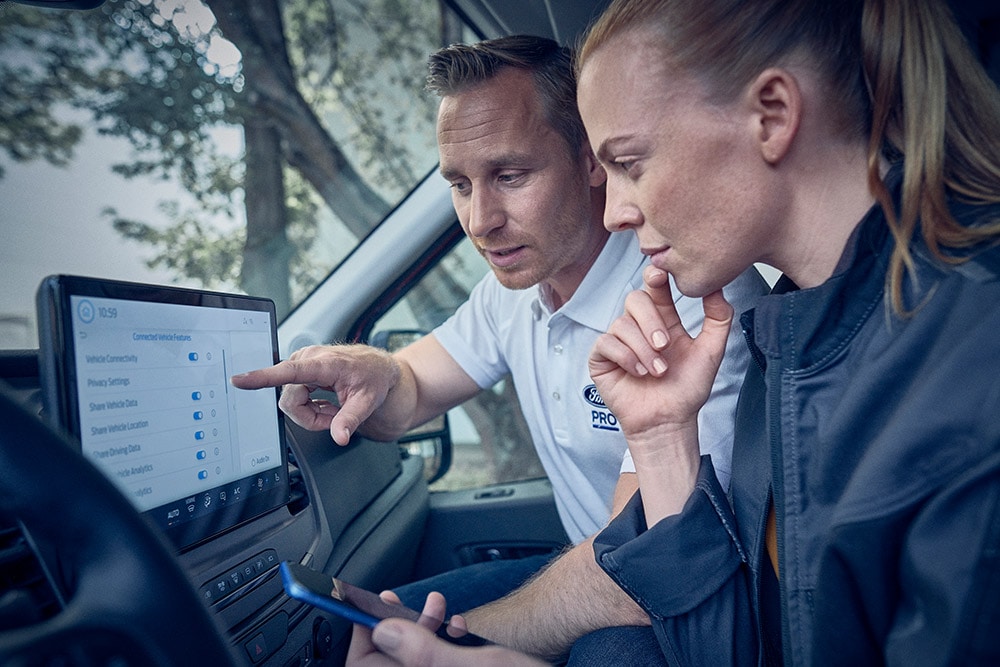Plusieurs véhicules électriques de la flotte Ford garés devant un entrepôt.