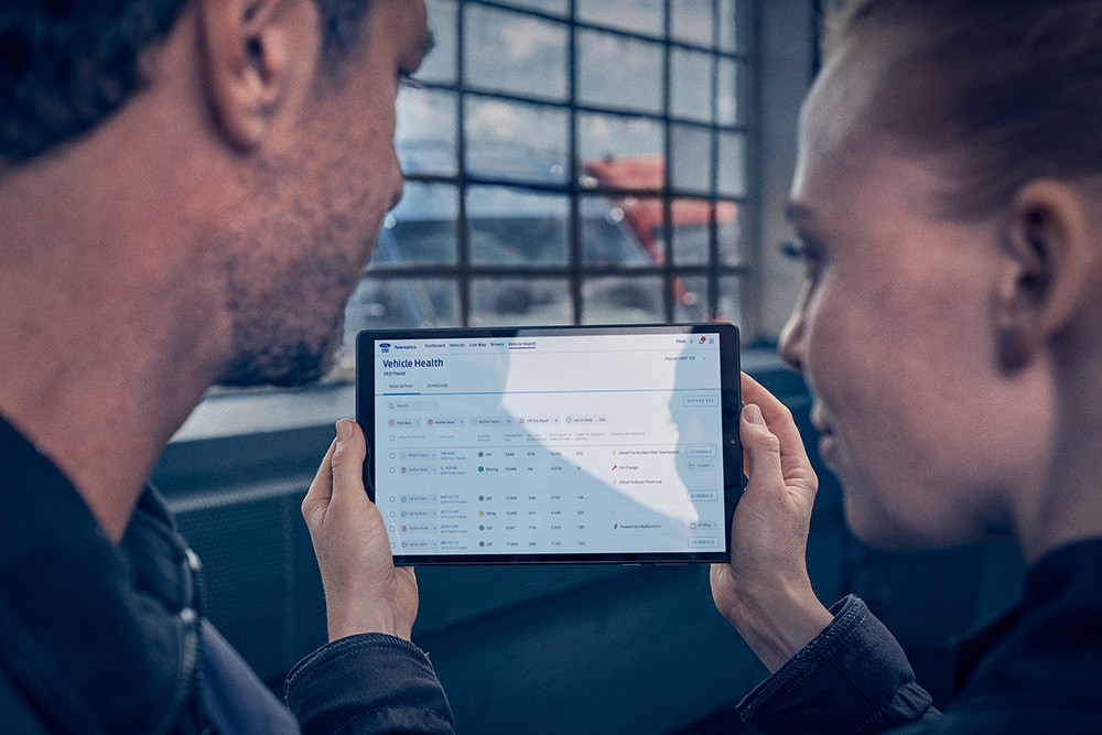 Gestionnaires de flotte consultant la télématique des véhicules sur une tablette.