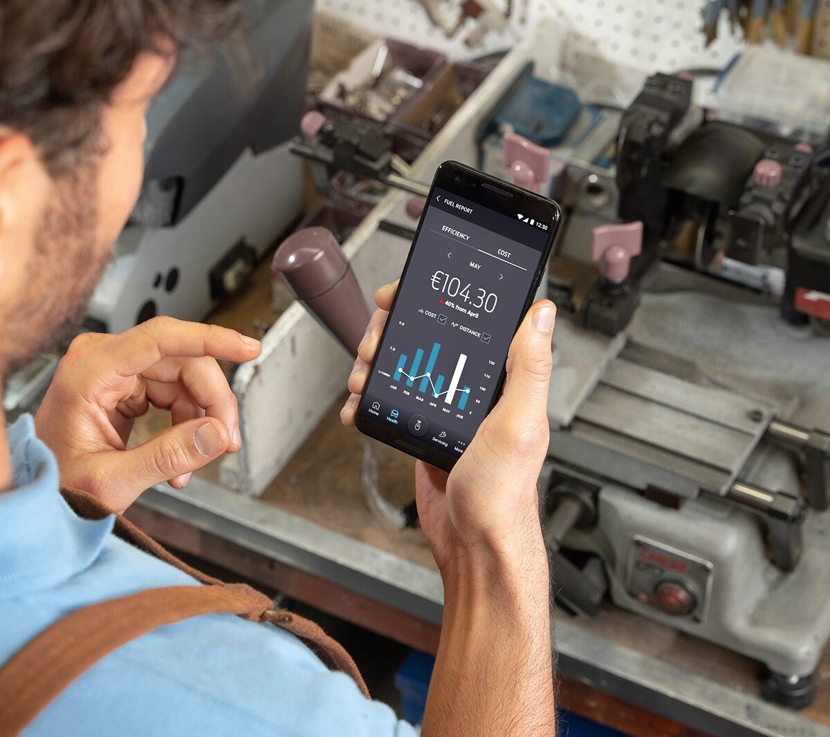 Un ouvrier dans un atelier regarde un téléphone portable dans sa main