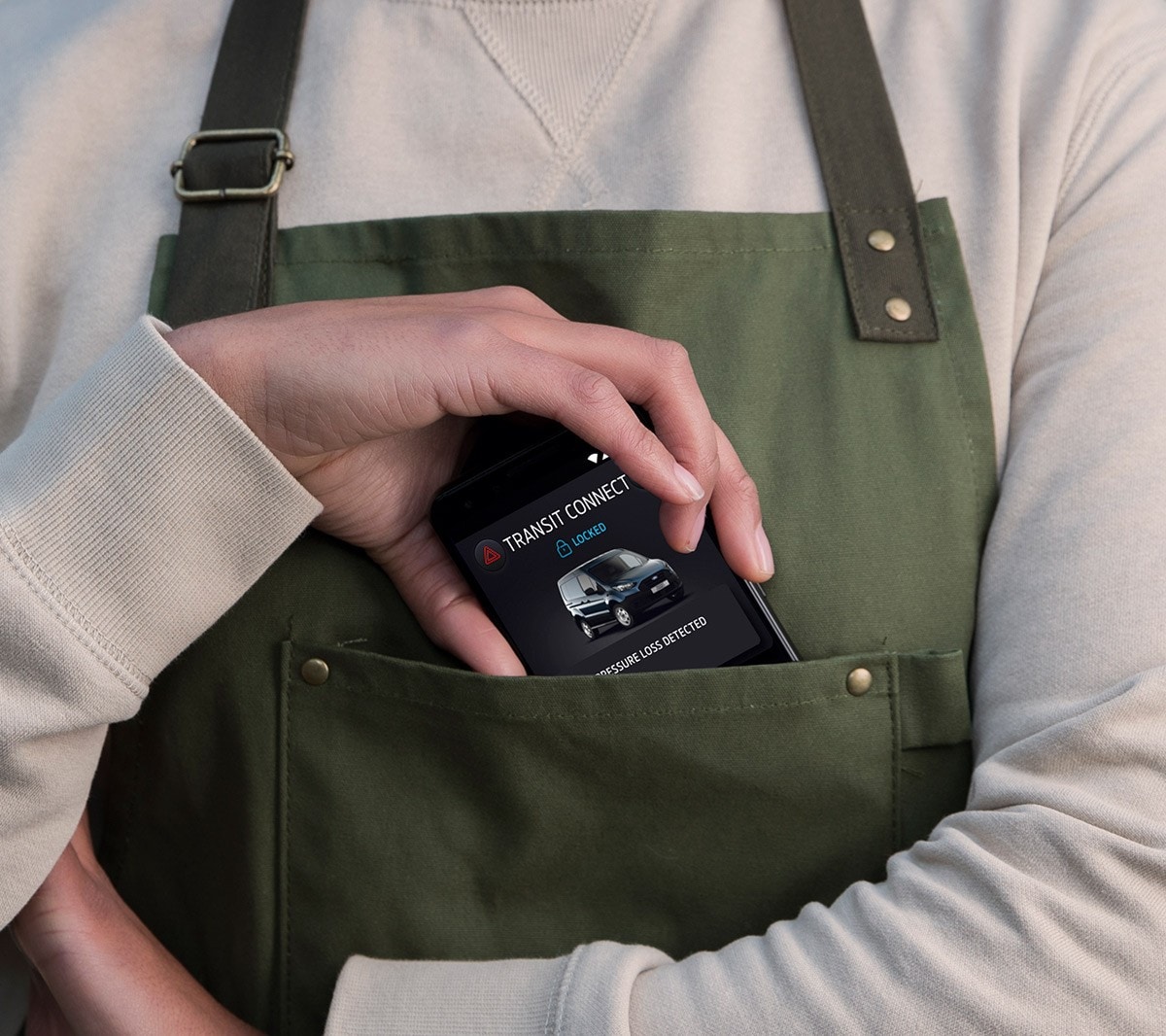 Vue detaillée sur une main qui glisse un téléphone portable dans la poche d'une blouse.