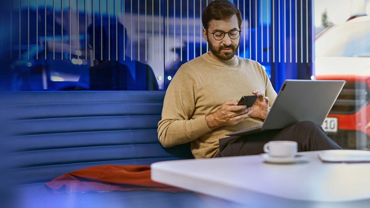 Un homme assis à une table avec un ordinateur portable et un téléphone mobile dans un bureau moderne